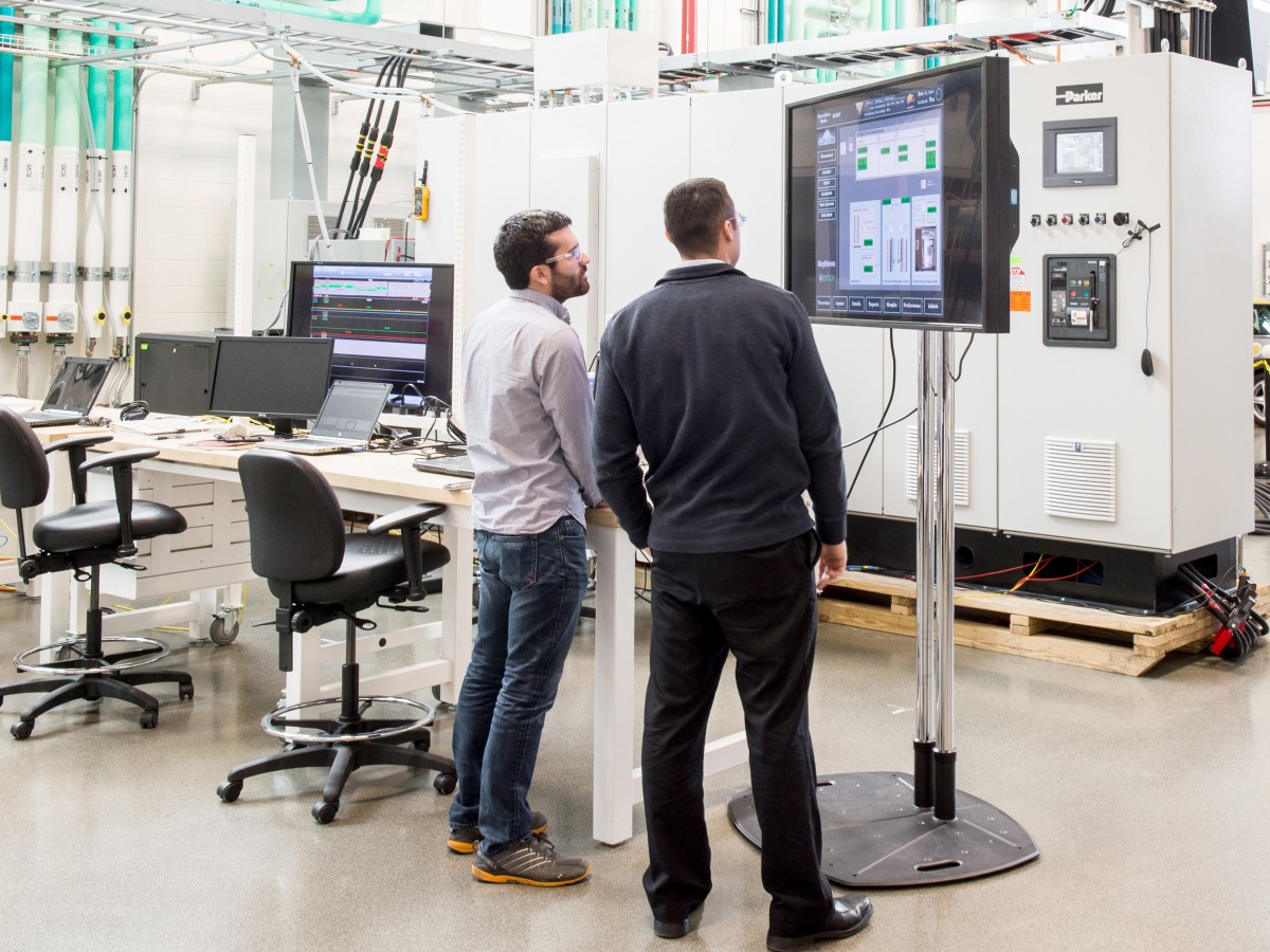 Men standing in front of devices.